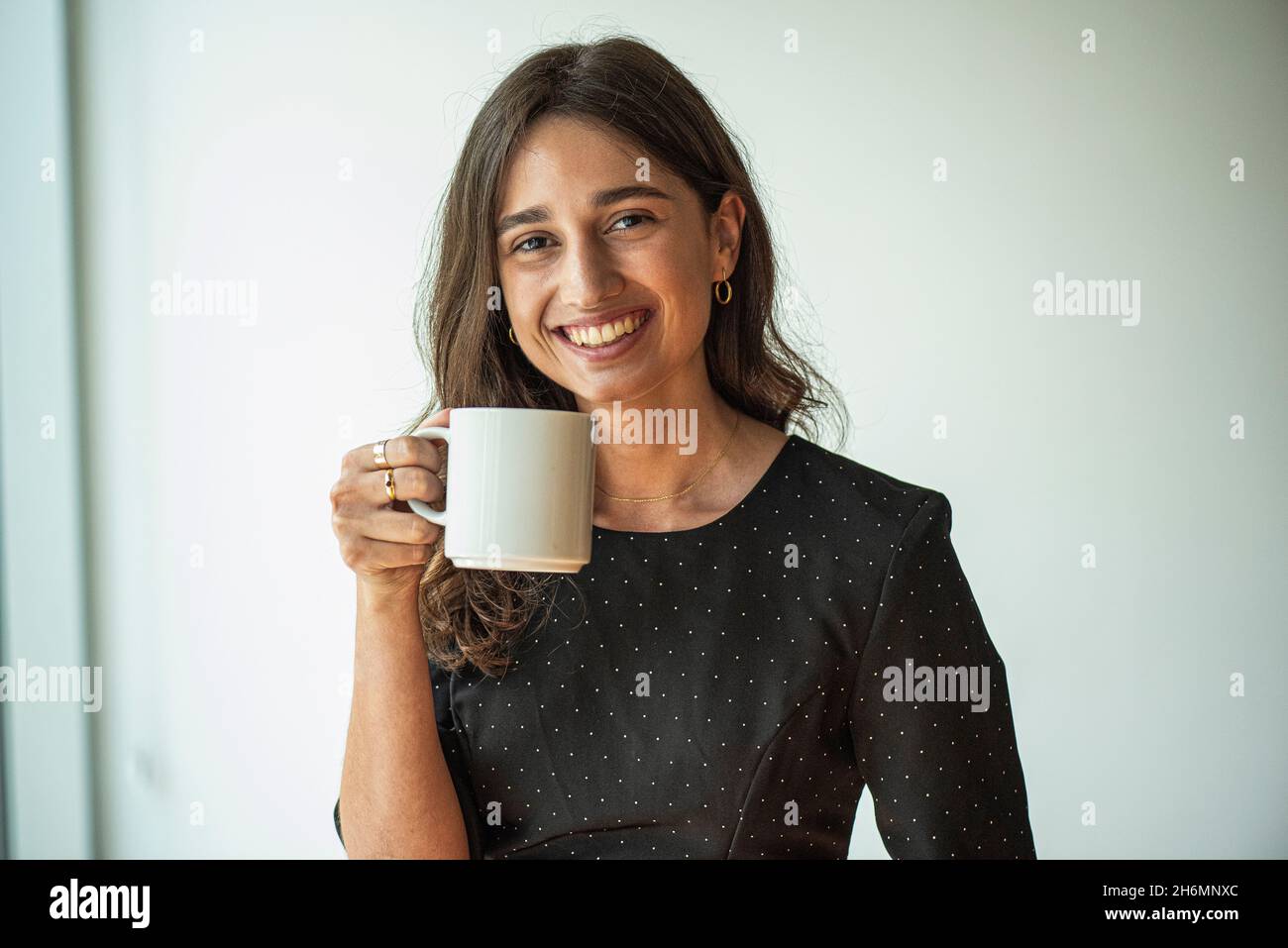 Portrait of smiling young woman holding a coffee cup Stock Photo