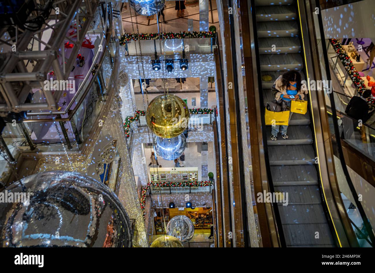 A woman shopper on the escalator in Selfridges Department Store in Oxford Street, London, UK  at Christmas surrounded by huge decorations.  Selfridges Stock Photo