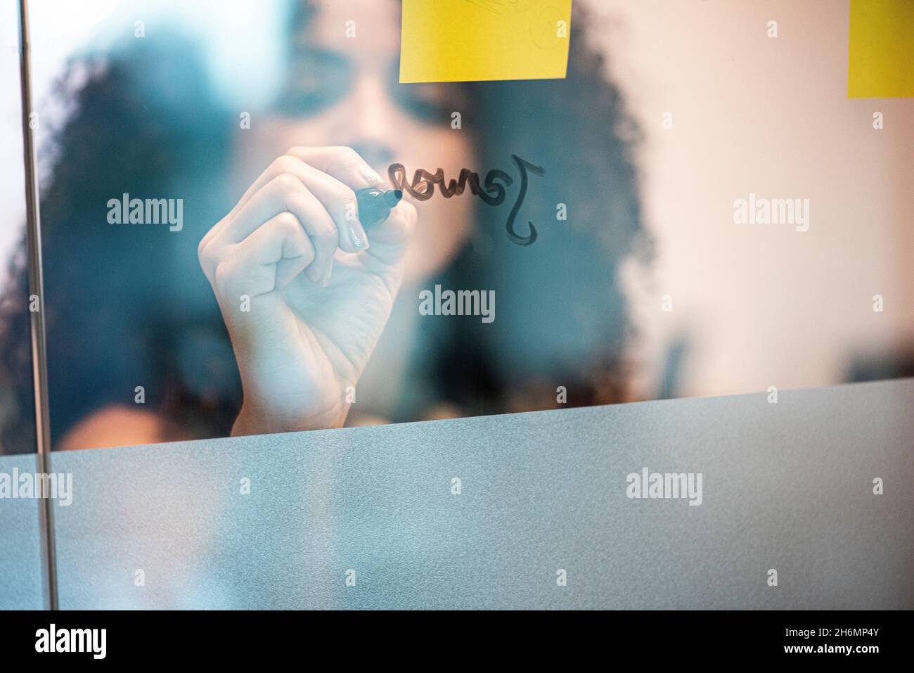 Businesswoman writing on glass wall in office Stock Photo