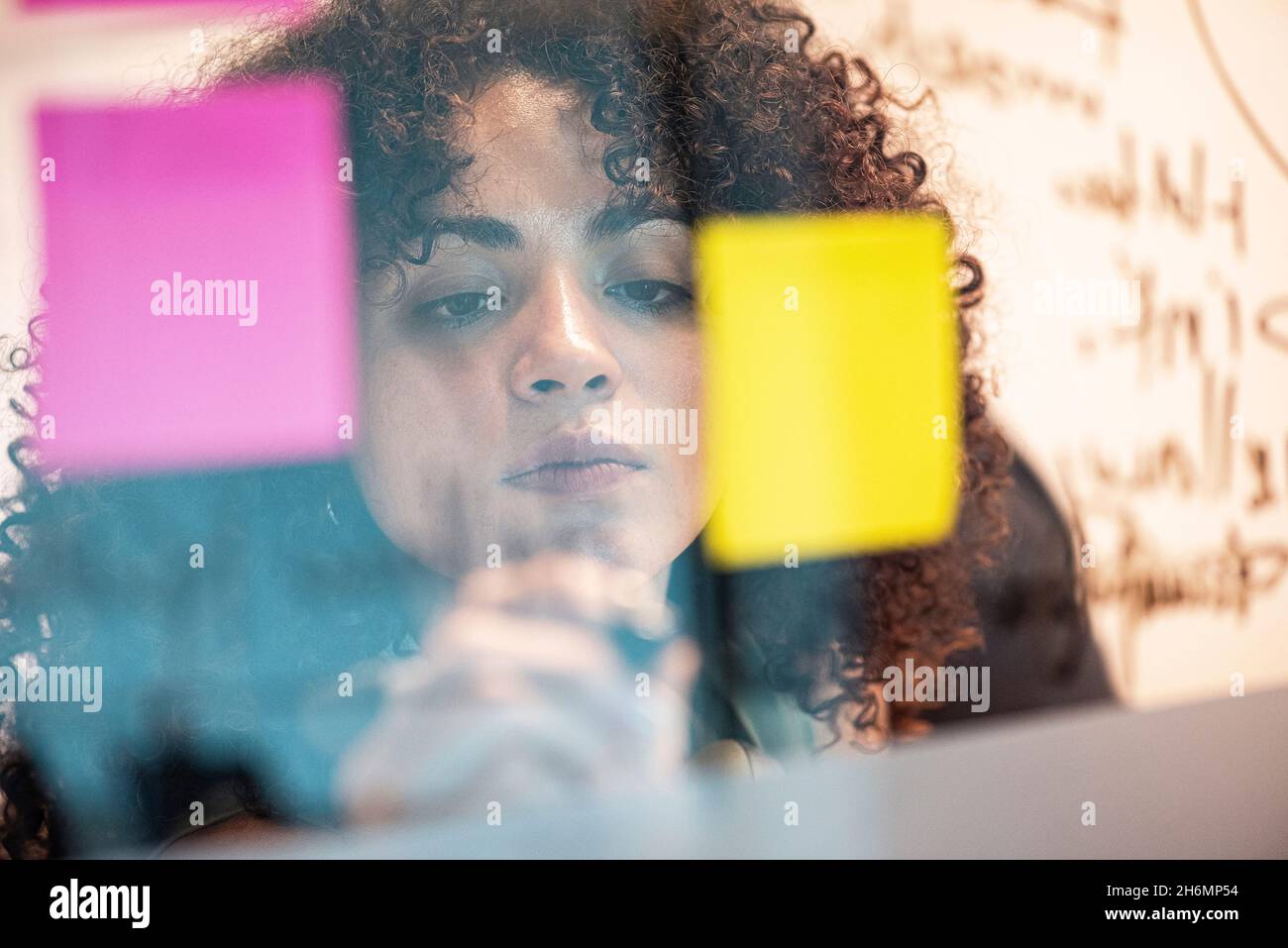 Businesswoman picking up a post it in office Stock Photo