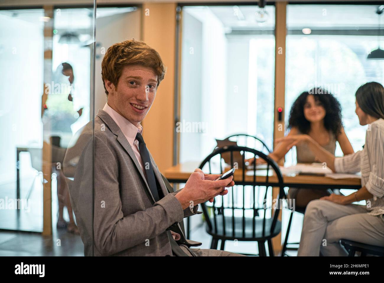 Smiling businessman using smart phone in office Stock Photo