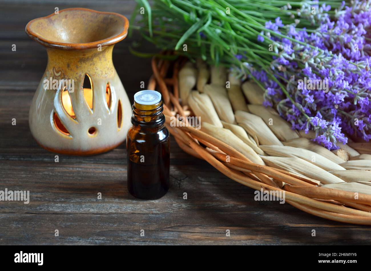 Fresh lavender flowers with essential oil bottle and a lamp for aromatic oils on a wooden table. Aromatherapy and spa concept. Stock Photo
