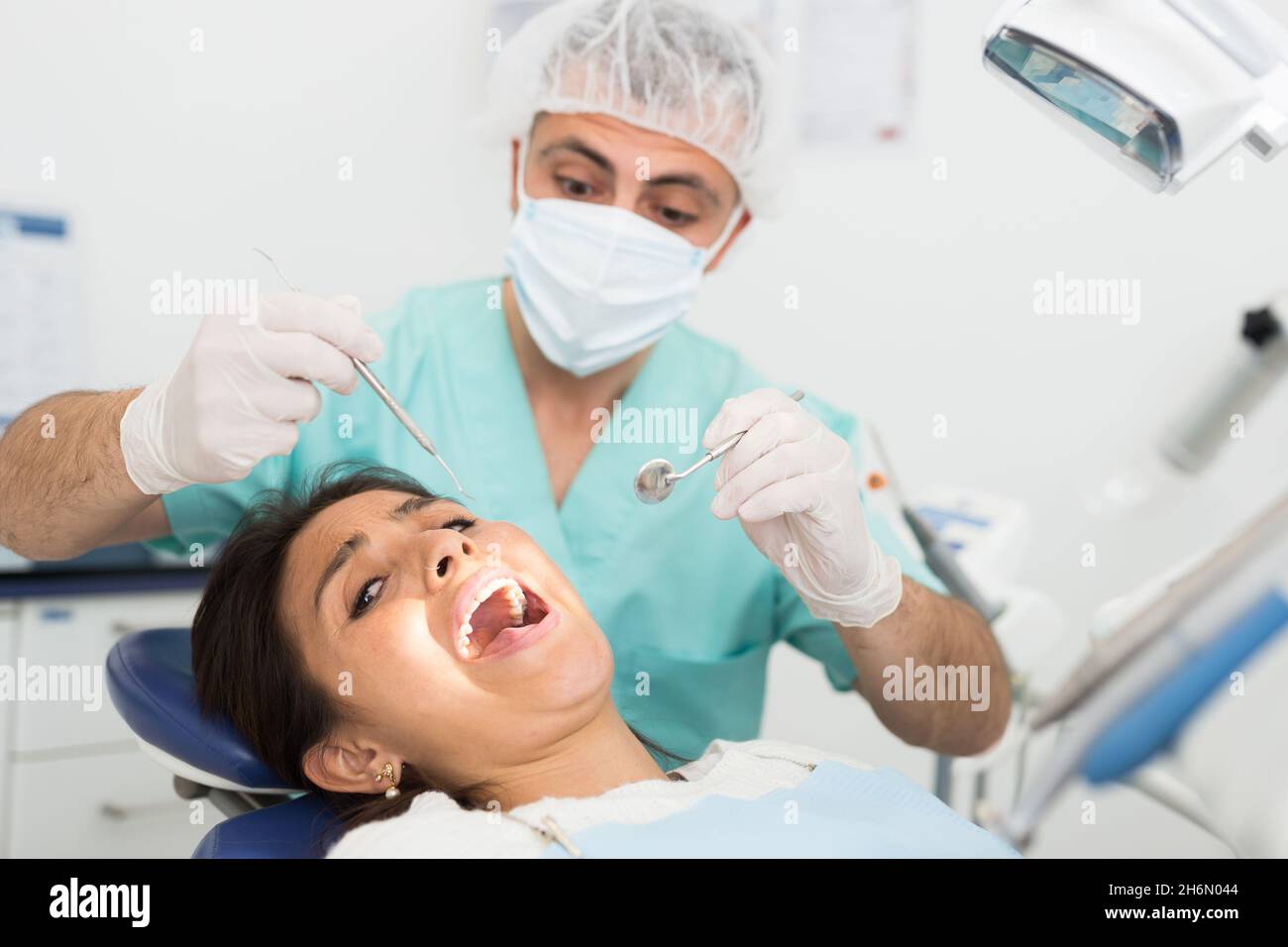 Dentist man examining a latin female patient teeth Stock Photo Alamy