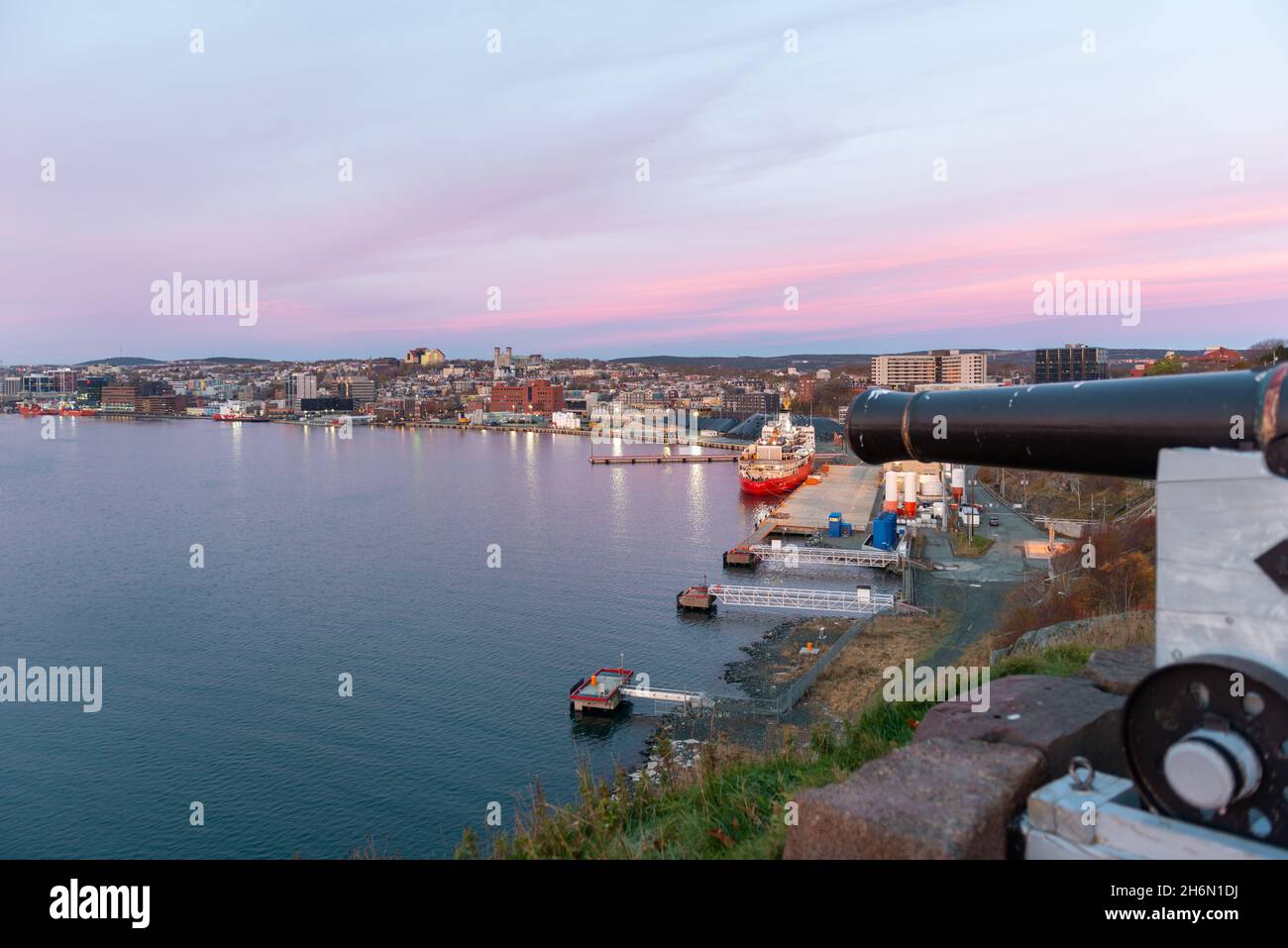 An evening pink sky overlooking St. John's Harbour with the Canadian Coast Guard Ship, Louis St Laurent, and oil and gas supply vessels moored in port. Stock Photo