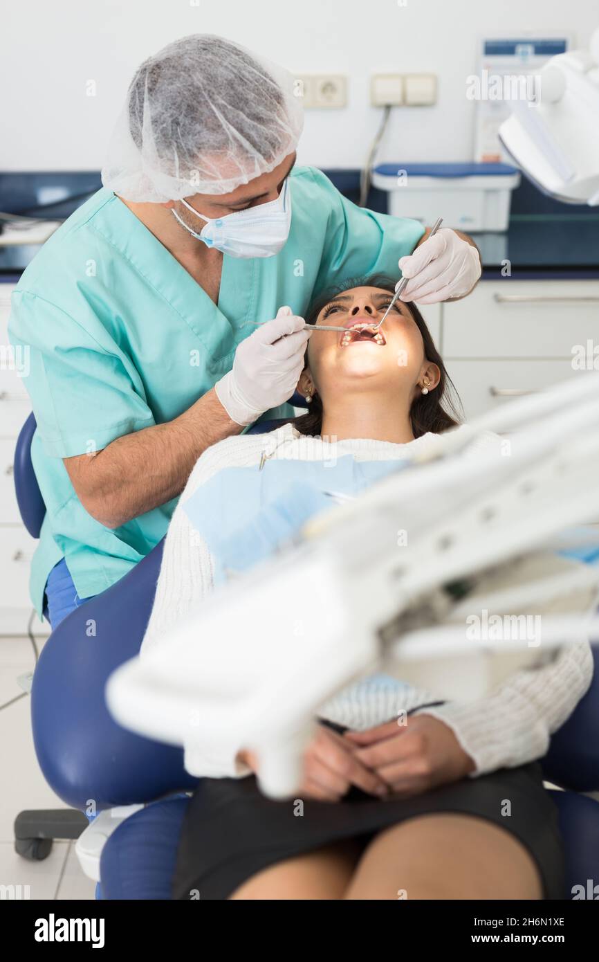 Dentist man examining a latin female patient teeth Stock Photo Alamy