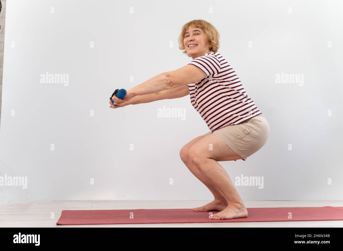 Elderly woman doing squats on a white background. The old lady is doing  exercises for her health Stock Photo - Alamy