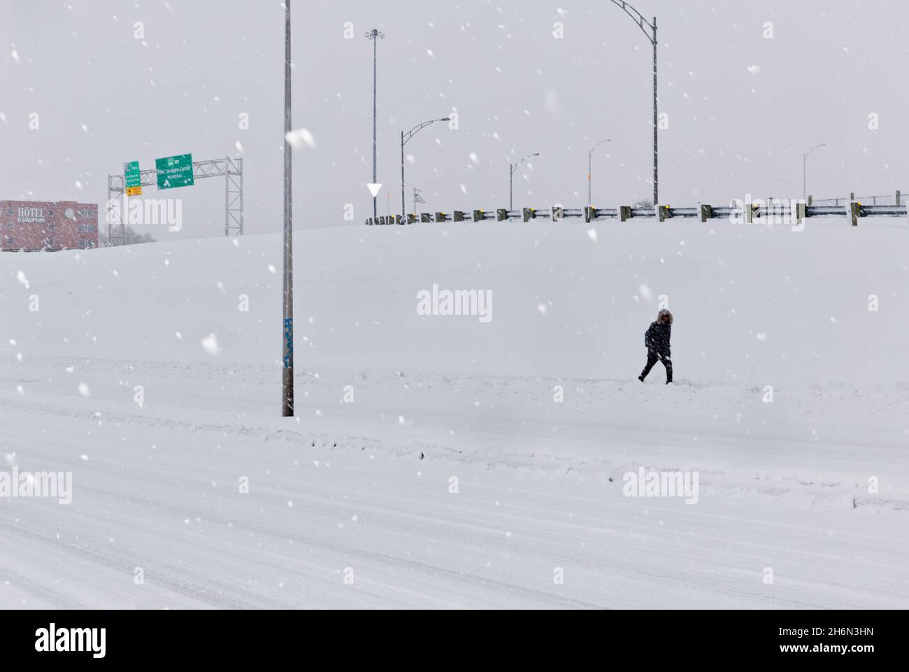 A lone pedestrian walks through falling snow in Longueuil, Quebec