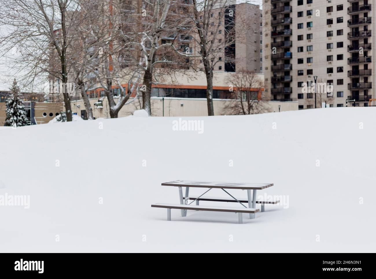Empty picnic table at a snowcovered playground in a residential area