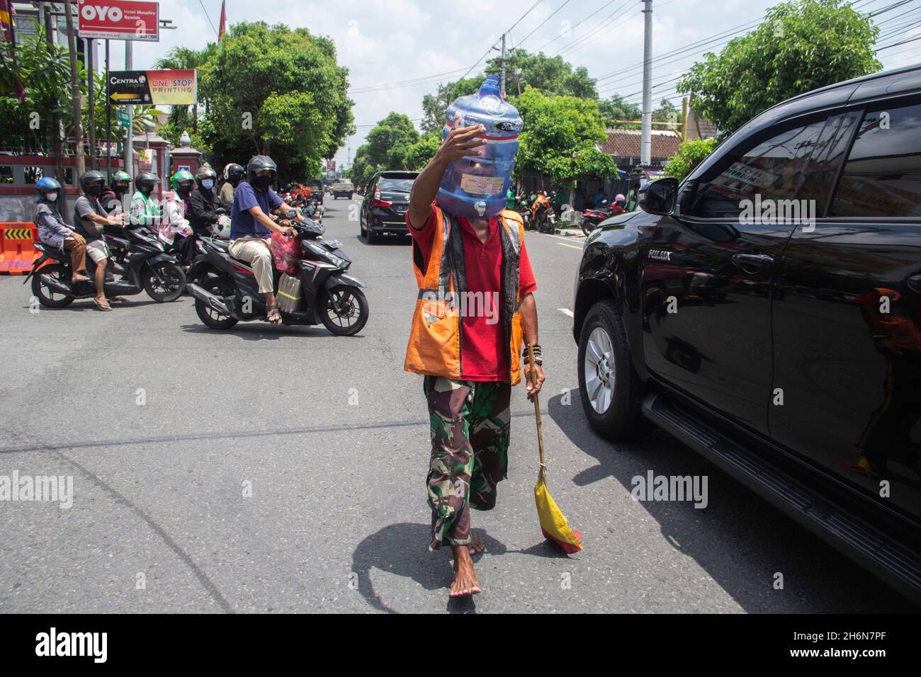 Yogyakarta, Yogyakarta, Indonesia. 4th Nov, 2021. Ali Akbar (52) Traffic Control Volunteer (Supeltas) uses a gallon of mineral water on his head to protect himself from the COVID-19 outbreak while controlling traffic in Yogyakarta, Indonesia on Thursday, November 4, 2021. Indonesia has more than 200 million vaccination targets covid-19 and more than 63% of Indonesia's population has received the covid-19 vaccine. The Indonesian government hopes that with this vaccine, the Indonesian economy will recover soon. (Credit Image: © Slamet Riyadi/ZUMA Press Wire) Stock Photo