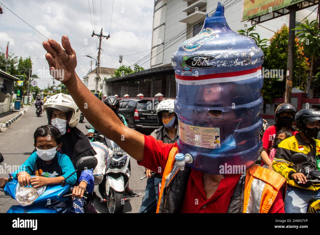 Yogyakarta, Yogyakarta Special Region, Indonesia. 4th Nov, 2021. Ali Akbar (52) Traffic Control Volunteer (Supeltas) uses a gallon of mineral water on his head to protect himself from the COVID-19 outbreak while controlling traffic in Yogyakarta, Indonesia on Thursday, November 4, 2021. Indonesia has more than 200 million vaccination targets covid-19 and more than 63% of Indonesia's population has received the covid-19 vaccine. The Indonesian government hopes that with this vaccine, the Indonesian economy will recover soon. (Credit Image: © Slamet Riyadi/ZUMA Press Wire) Stock Photo
