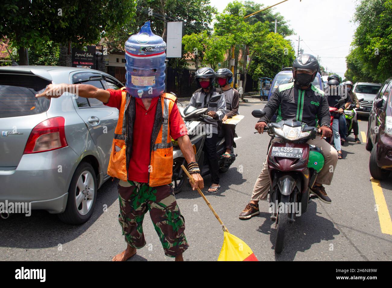 Yogyakarta, Yogyakarta, Indonesia. 4th Nov, 2021. Ali Akbar (52) Traffic Control Volunteer (Supeltas) uses a gallon of mineral water on his head to protect himself from the COVID-19 outbreak while controlling traffic in Yogyakarta, Indonesia on Thursday, November 4, 2021. Indonesia has more than 200 million vaccination targets covid-19 and more than 63% of Indonesia's population has received the covid-19 vaccine. The Indonesian government hopes that with this vaccine, the Indonesian economy will recover soon. (Credit Image: © Slamet Riyadi/ZUMA Press Wire) Stock Photo