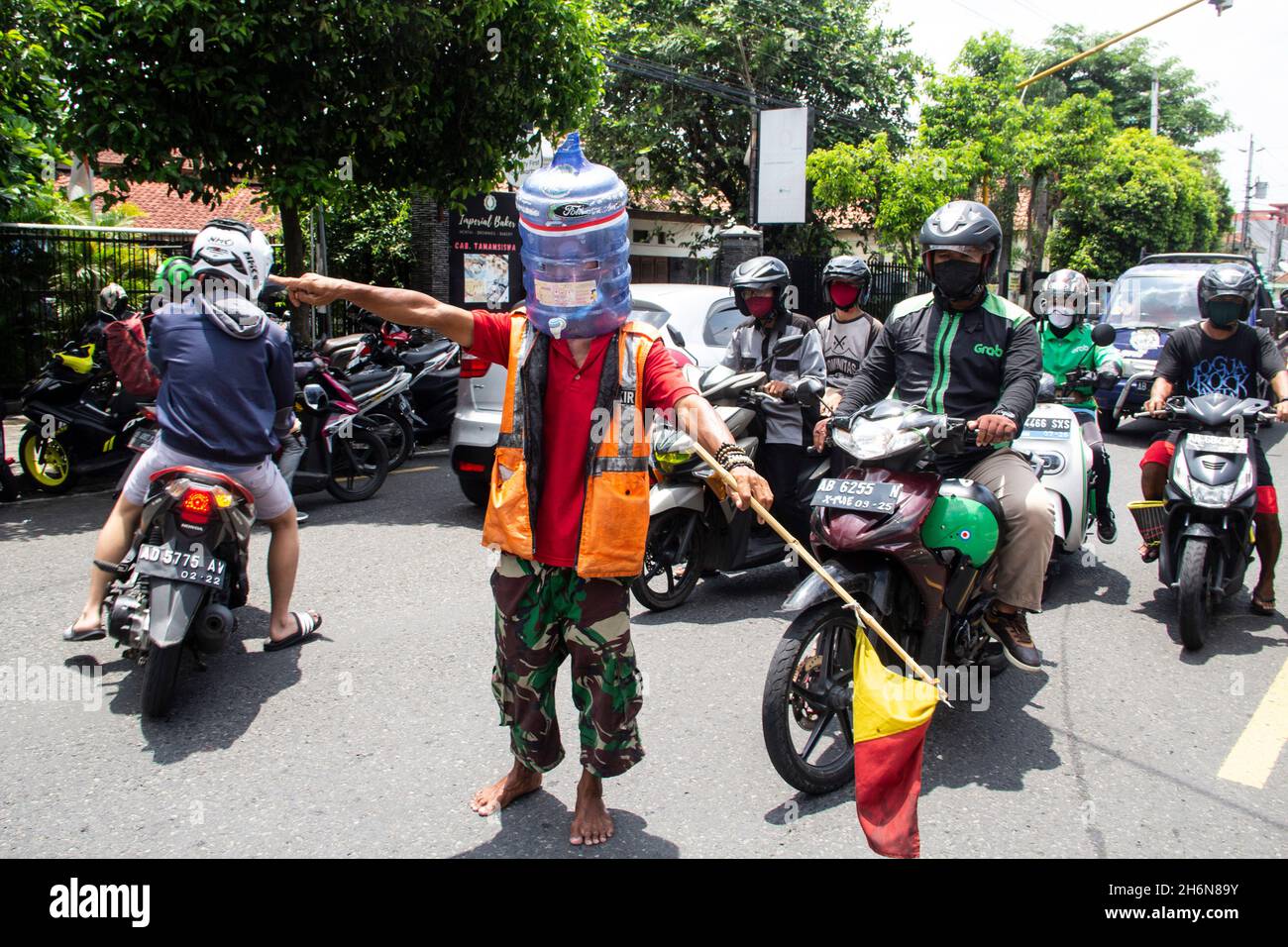 Yogyakarta, Yogyakarta, Indonesia. 4th Nov, 2021. Ali Akbar (52) Traffic Control Volunteer (Supeltas) uses a gallon of mineral water on his head to protect himself from the COVID-19 outbreak while controlling traffic in Yogyakarta, Indonesia on Thursday, November 4, 2021. Indonesia has more than 200 million vaccination targets covid-19 and more than 63% of Indonesia's population has received the covid-19 vaccine. The Indonesian government hopes that with this vaccine, the Indonesian economy will recover soon. (Credit Image: © Slamet Riyadi/ZUMA Press Wire) Stock Photo