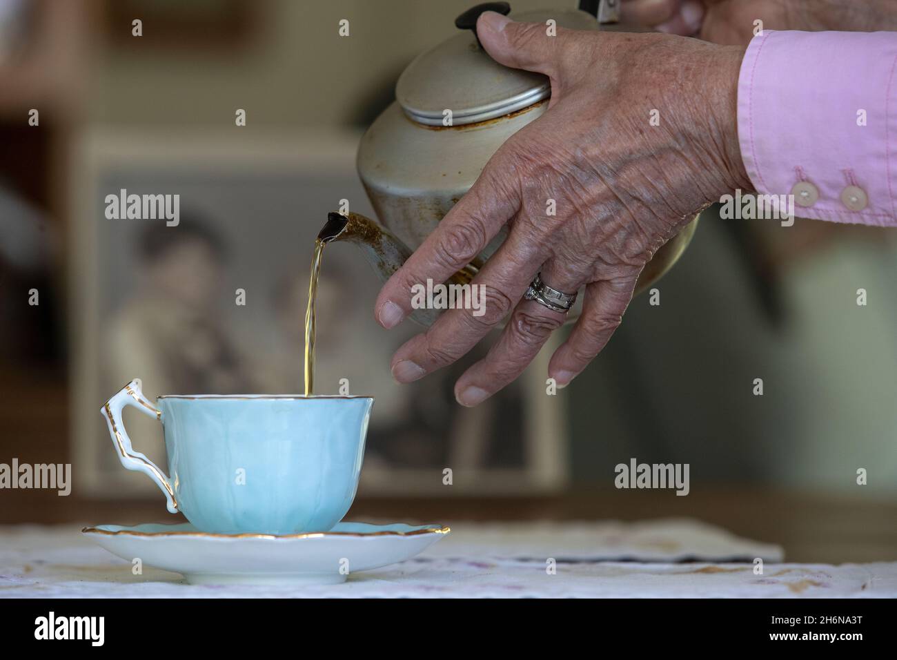 Generic photo of a females old hands pouring a cup of tea from a pot into a china cup. Stock Photo