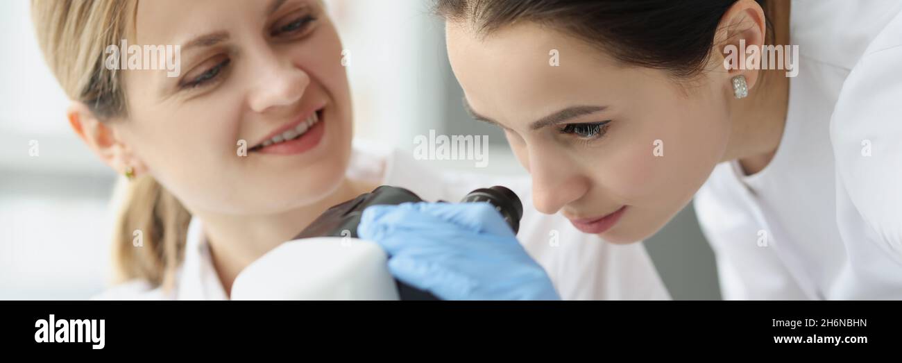 Female scientists chemists looking through microscope in laboratory Stock Photo