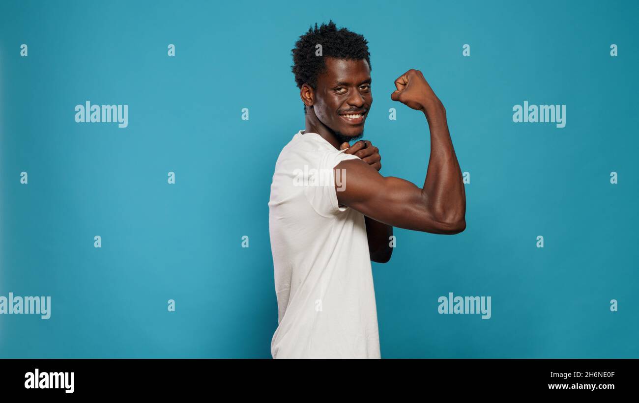 Athletic person flexing biceps muscles on camera in studio. Trained man  showing musculature on arms while standing over isolated background. Athlete  with muscular body from fitness Stock Photo - Alamy