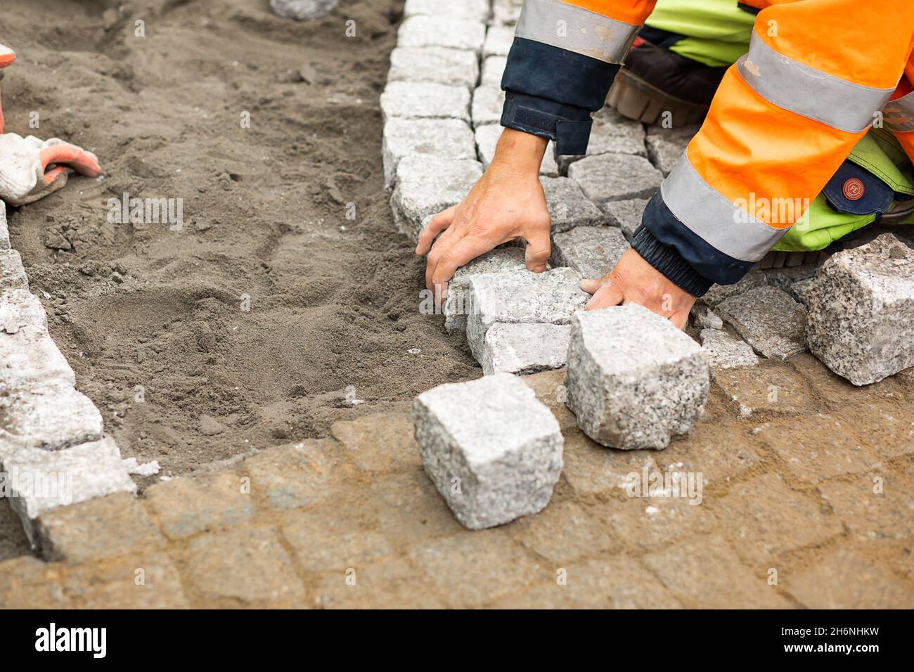 Maintenance work on paving with interlocking paving stones. Unrecognizable persons with building materials in hand, Concrete products, building indust Stock Photo