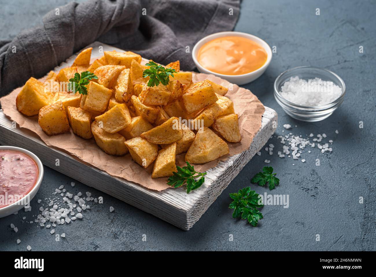 Patatas bravas with sauces and fresh herbs on a white board. Tapas
