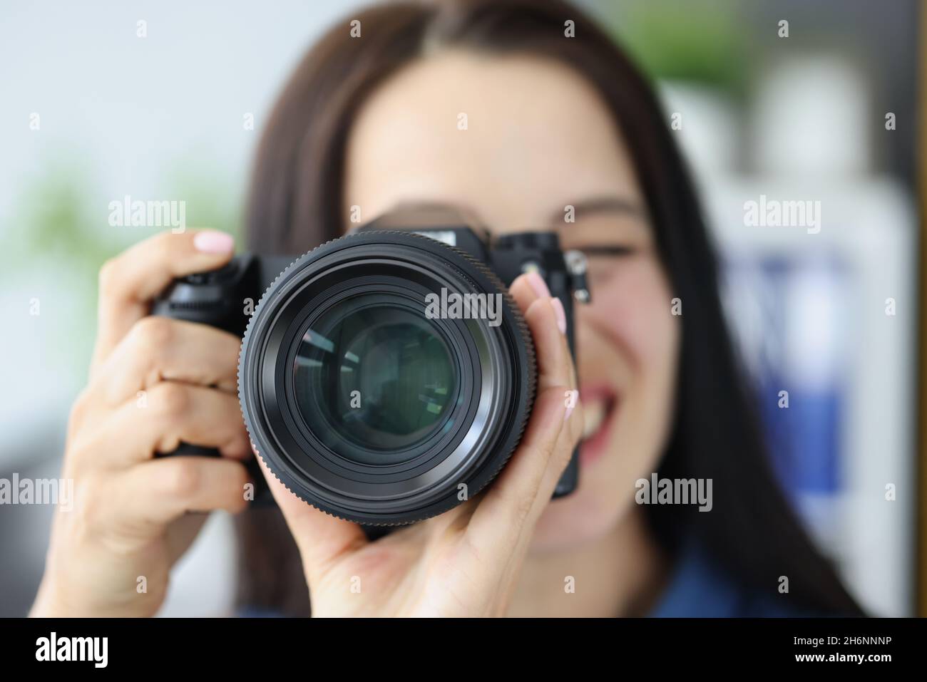 Smiling brunette female photographer pointing super wide lens at you Stock Photo