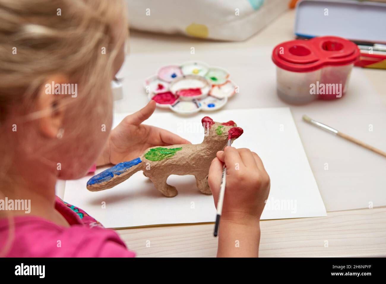 Girl and boy painting paper mache or gibs figurines. Child drawing with acrylic paint for her homeschooling art project crafts. Stock Photo