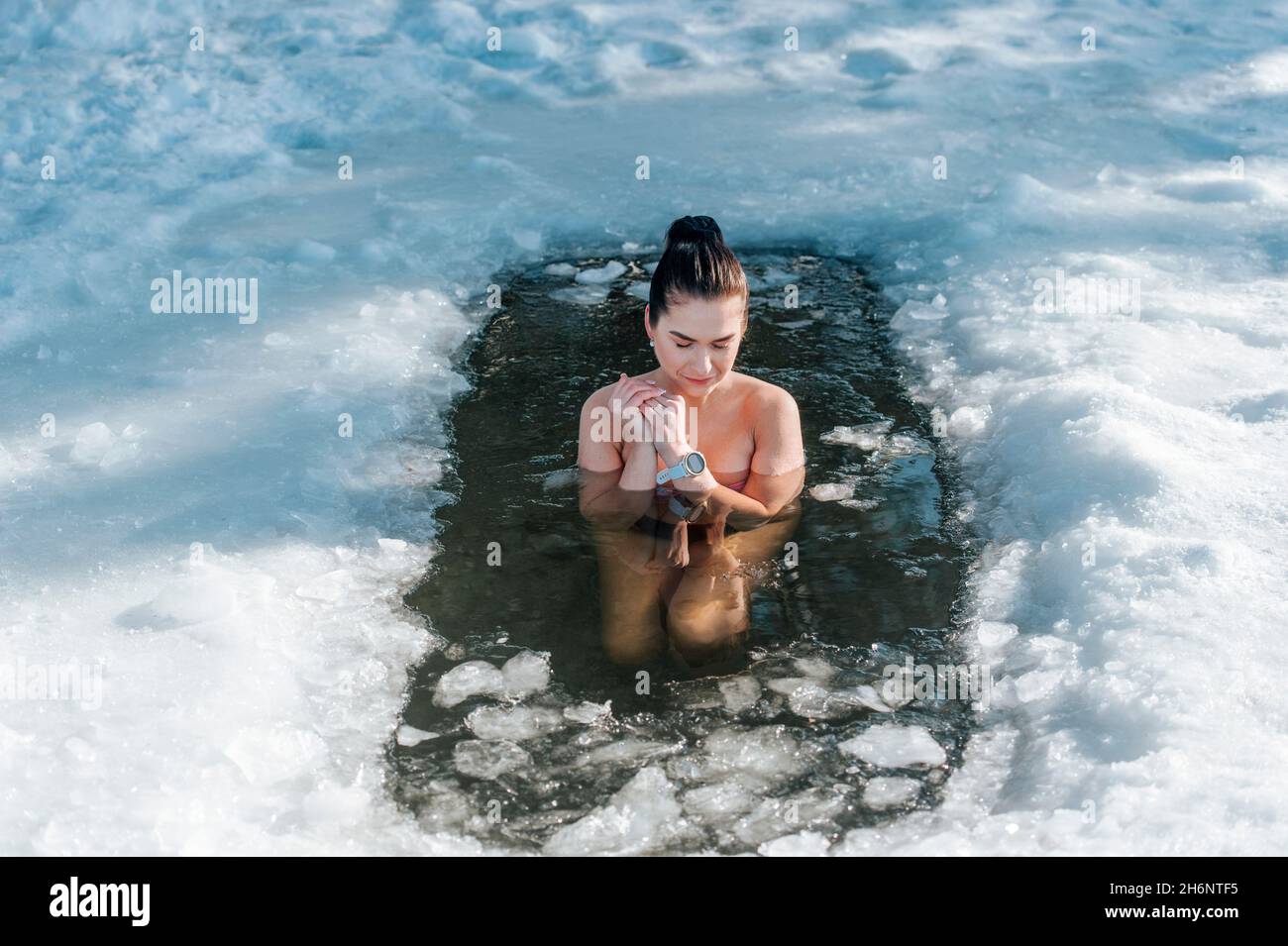 Girl with bikini and a watch in frozen lake ice hole. Woman hardening the  body in cold water. Good immunity is protection against many diseases.  Vinta Stock Photo - Alamy