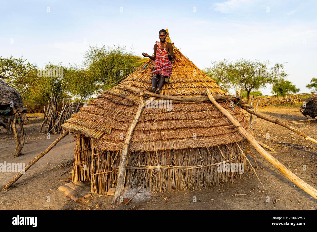 Woman repairing a roof of a traditional build hut of the Toposa tribe, Eastern Equatoria, South Sudan Stock Photo