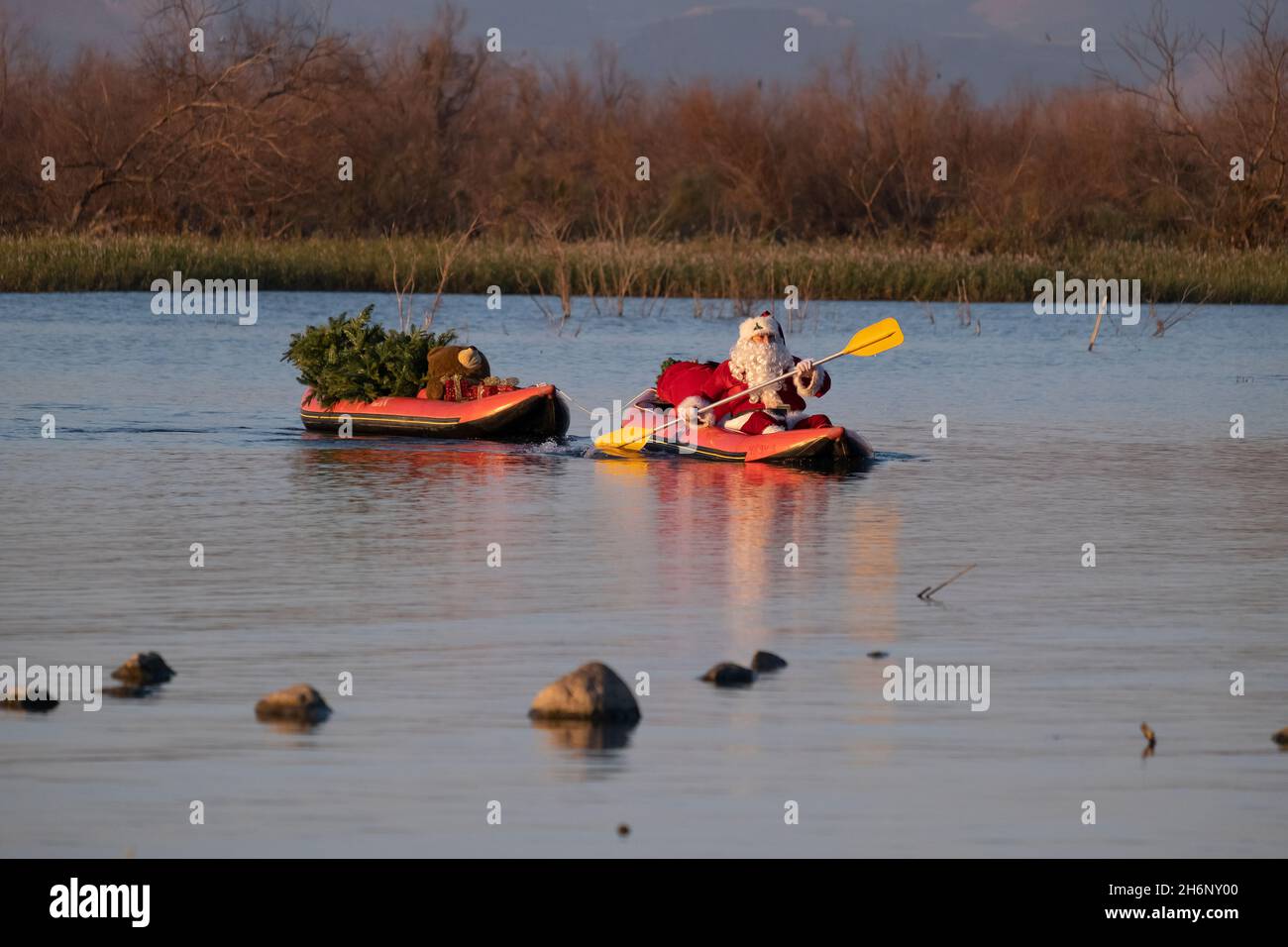 Issa Kassissieh, an Arab Orthodox Christian and Israel’s only certified Santa Claus, paddles with a Christmas tree and presents during the filming of a Christmas season advertisement for the Israeli ministry of tourism at the eastern side of the Sea of Galilee in Israel. Stock Photo