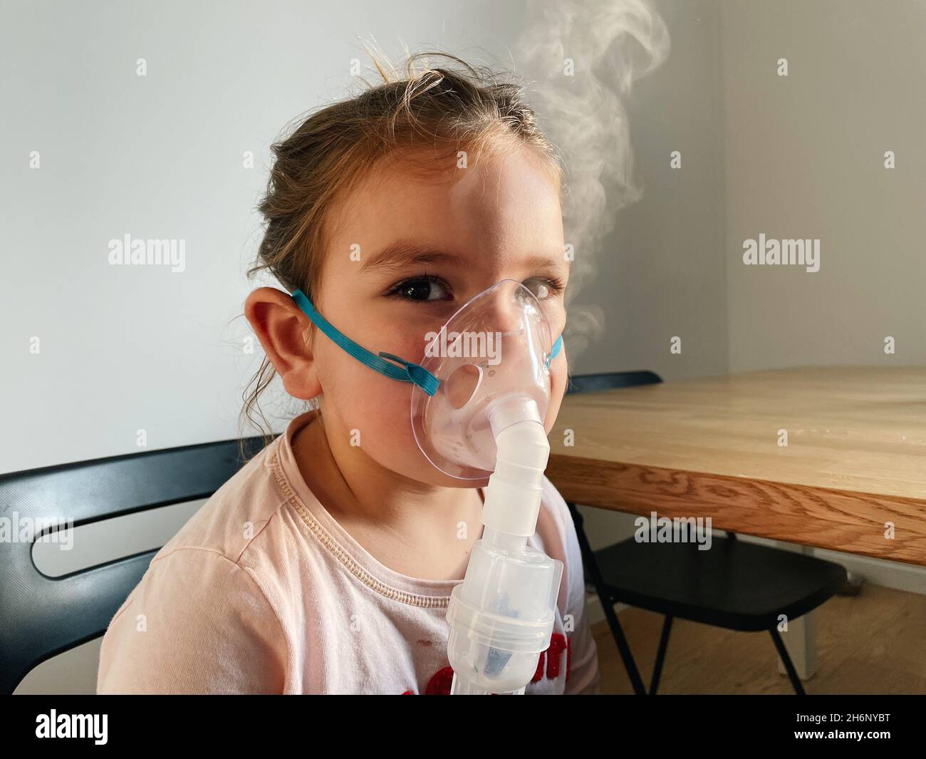 Sick adorable preschool girl with nebuliser mask at home. Treatment for