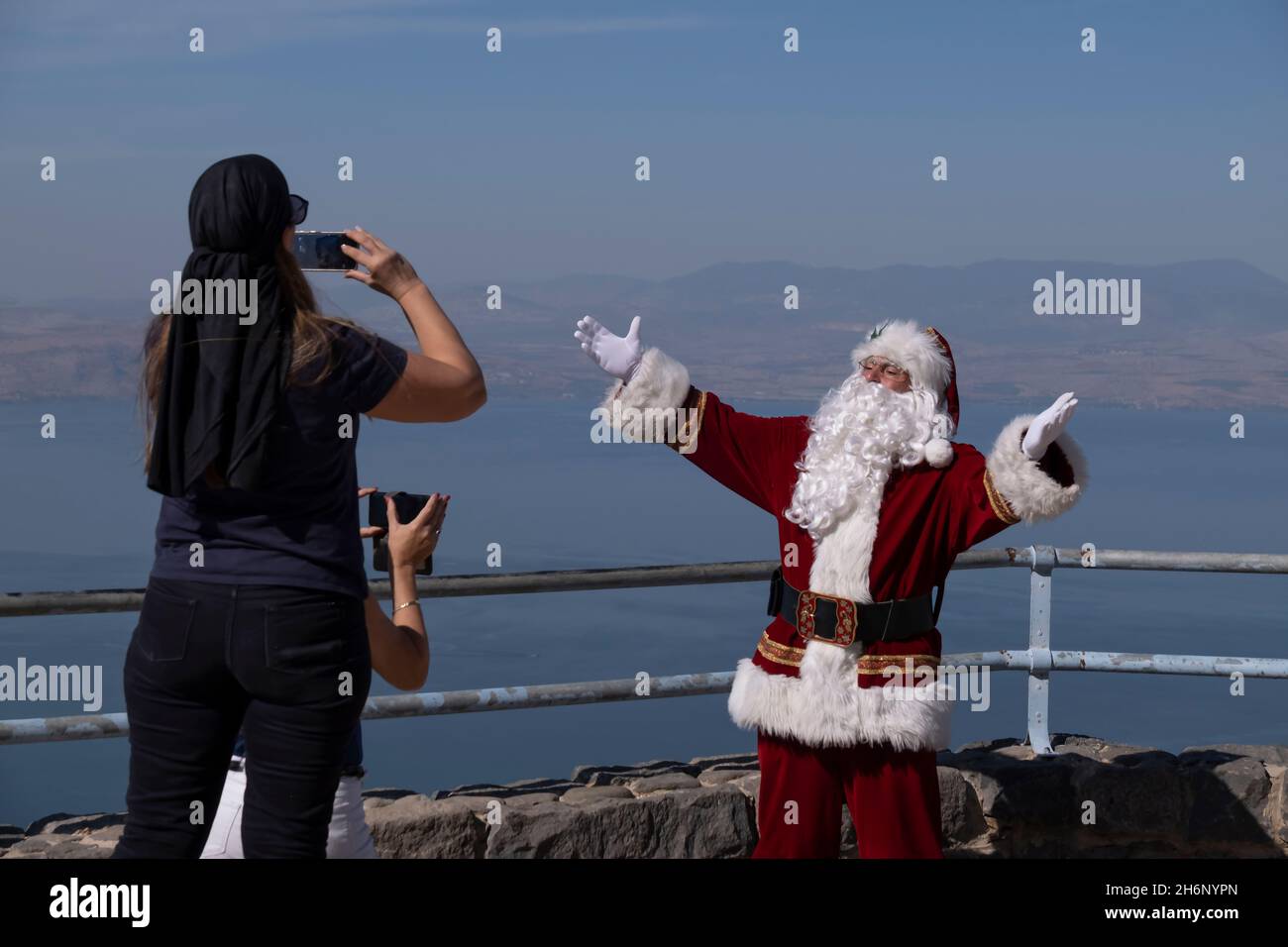Israeli women taking photo of Issa Kassissieh, an Arab Orthodox Christian and Israel’s only certified Santa Claus, at Mitzpe Shalom, also known as Peace Lookout located at the eastern side of the Sea of Galilee in Israel. Stock Photo