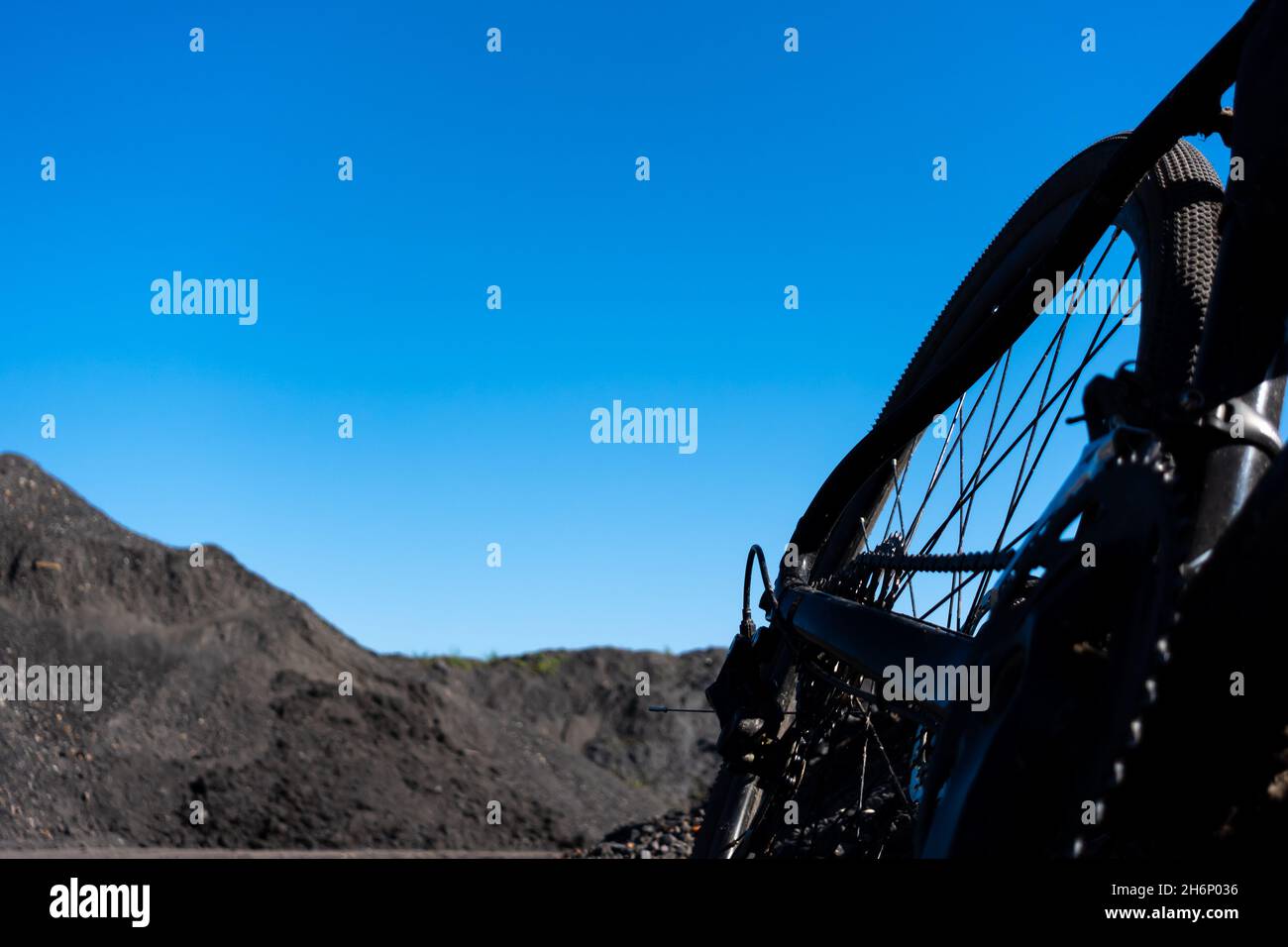 Gravel bike against background. of blue sky. Adventure on a gravel bike on the industrial area full of black gravel . Photo taken on a beautiful sunny Stock Photo