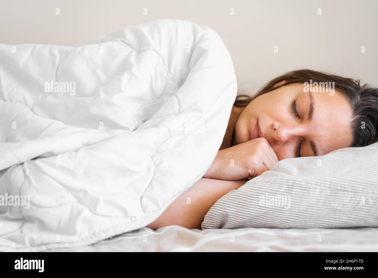 Young millennial woman sleeping covered with blanket. Cold winter. No