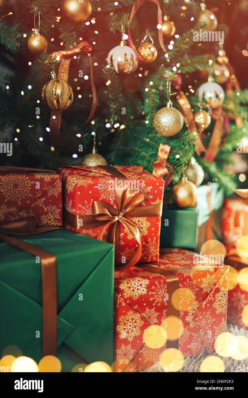 Many gift boxes with sequins standing under a decorated Christmas tree Stock Photo