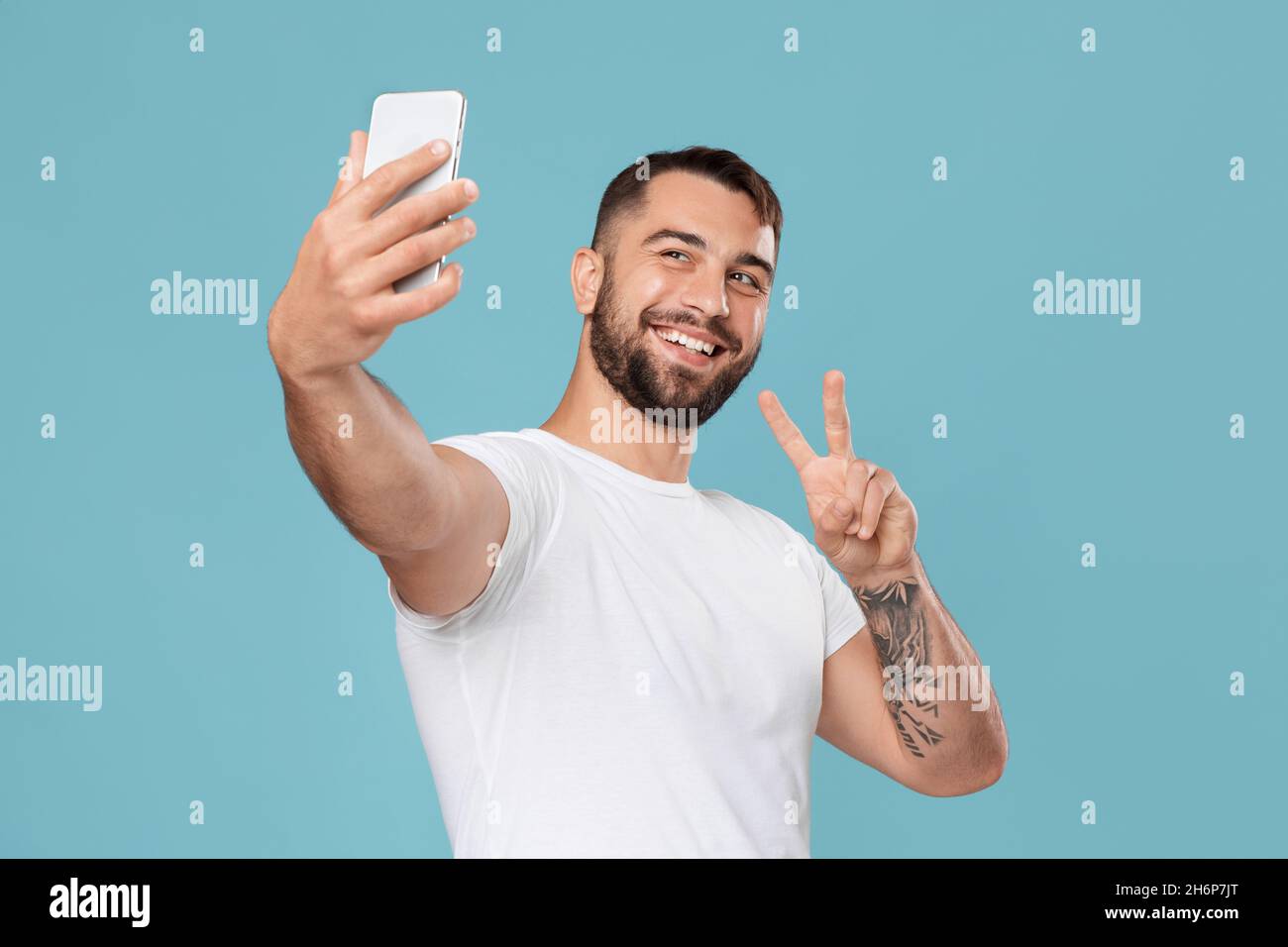 Happy mature caucasian man making video call on smartphone and showing peace sign to webcam Stock Photo