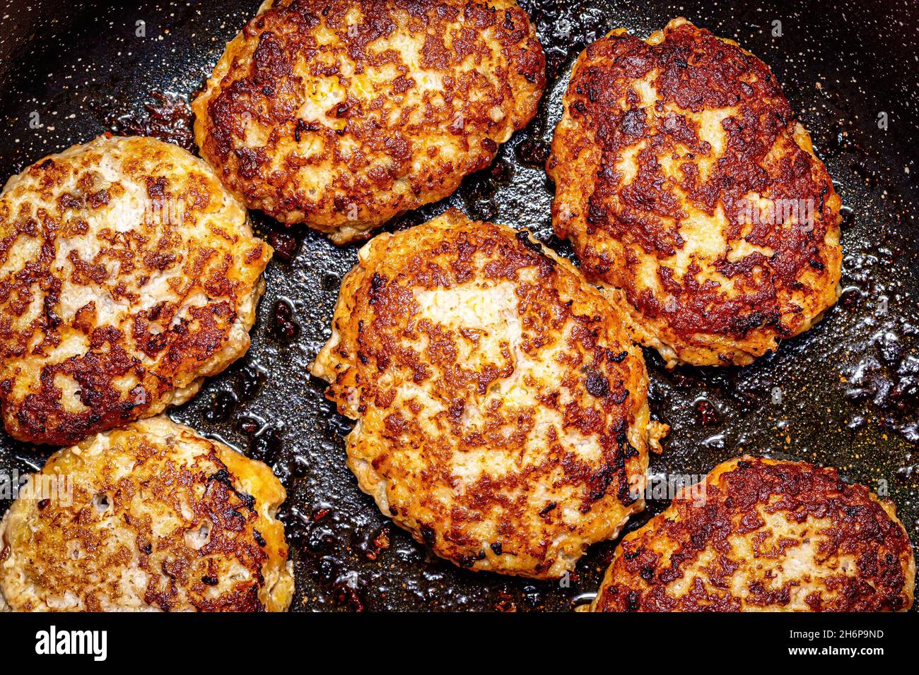 Raw white fish meat cutlets, heated in a ceramic black skillet with ...