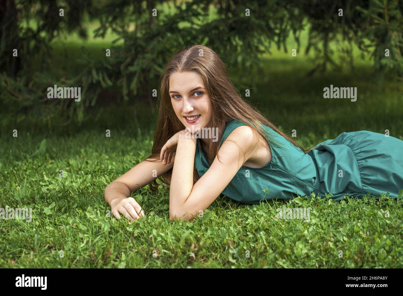 Close up portrait of a young girl lying on green grass, summer park ...