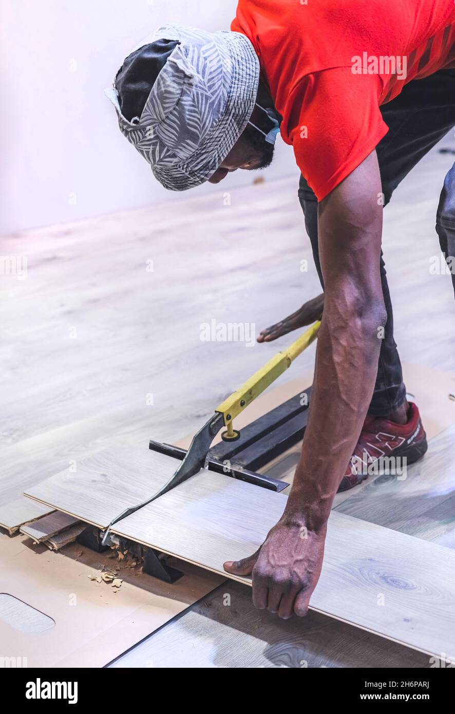Johannesburg, South Africa - 15th November, 2021: Man cutting flooring planks with a cutter. Stock Photo
