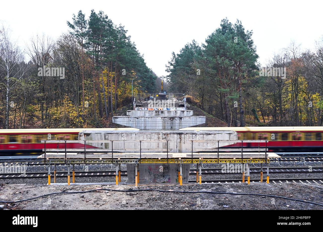 17 November 2021, Brandenburg, Hohen Neuendorf: A suburban train passes between the supporting pillars of the former bridge of the L 171 state road. The bridge between Hohen Neuendorf and Bergfelde, built in the 1960s, had to be demolished because damage to the prefabricated prestressed concrete girders was discovered during a special inspection. According to the Landesbetriebes Straßenwesen, it could not be ruled out that concrete parts would fall onto the tracks or passing trains. It is planned that a temporary bridge will be built in the spring of 2022 year. The individual segments are alre Stock Photo
