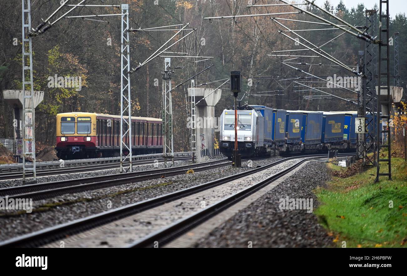 17 November 2021, Brandenburg, Hohen Neuendorf: A suburban train and a freight train pass simultaneously between the supporting pillars of the former bridge of the L 171 state road. The bridge between Hohen Neuendorf and Bergfelde, built in the 1960s, had to be demolished because damage to the prefabricated prestressed concrete girders was discovered during a special inspection. According to the Landesbetriebes Straßenwesen, it could not be ruled out that concrete parts would fall onto the tracks or passing trains. It is planned that a temporary bridge will be built in the spring of 2022 year. Stock Photo