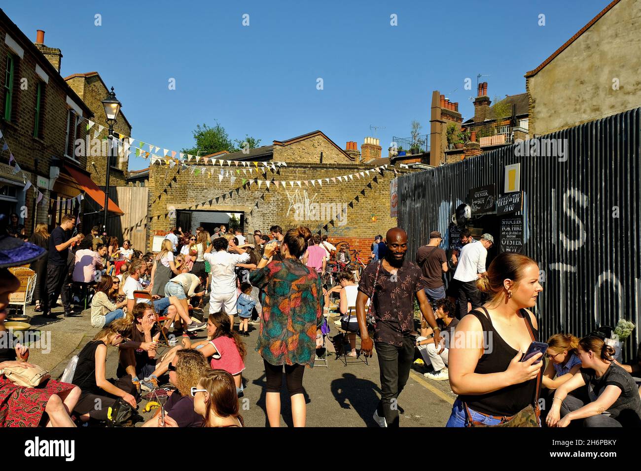 London, Great Britain - May 20, 2018 : Young people having fun drinking  and listening to street musicians in Hackney, East London on a sunny day Stock Photo