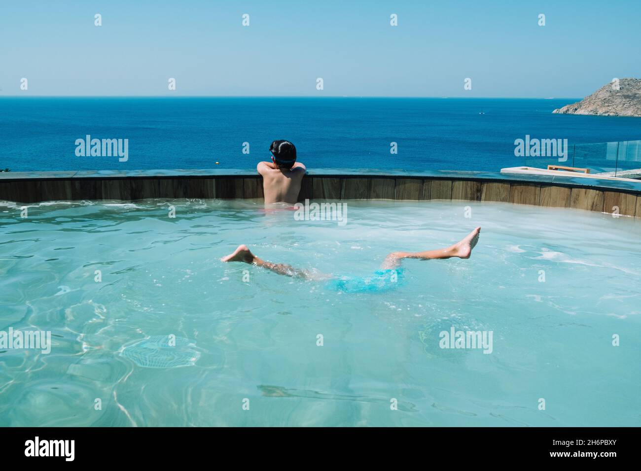 kids diving and playing in pool over looking blue sea Stock Photo