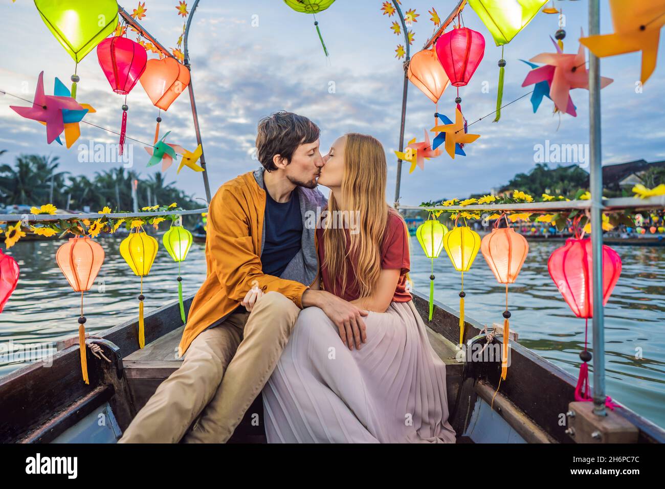 Happy couple of travelers ride a national boat on background of Hoi An ...