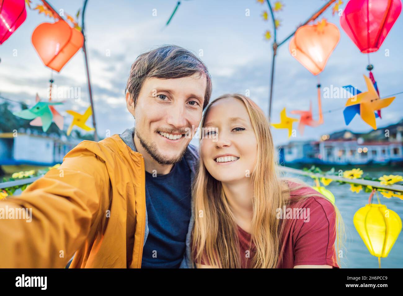 Happy couple of travelers ride a national boat on background of Hoi An ...
