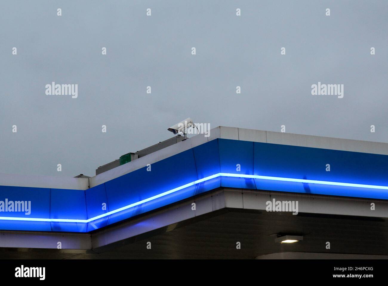 Blau beleuchtetes Dach mit einer Überwachungskamera einer ARAL Tankstelle bei Nacht. Stock Photo