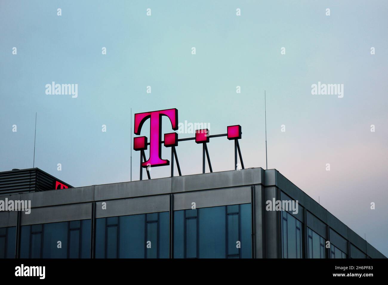 Das magenta farbene, leuchtende Telekom Logo der 'Deutsche Telekom AG' auf dem Dach des Gebäudes der Telekom in der Abenddämmerung in Düsseldorf. Stock Photo