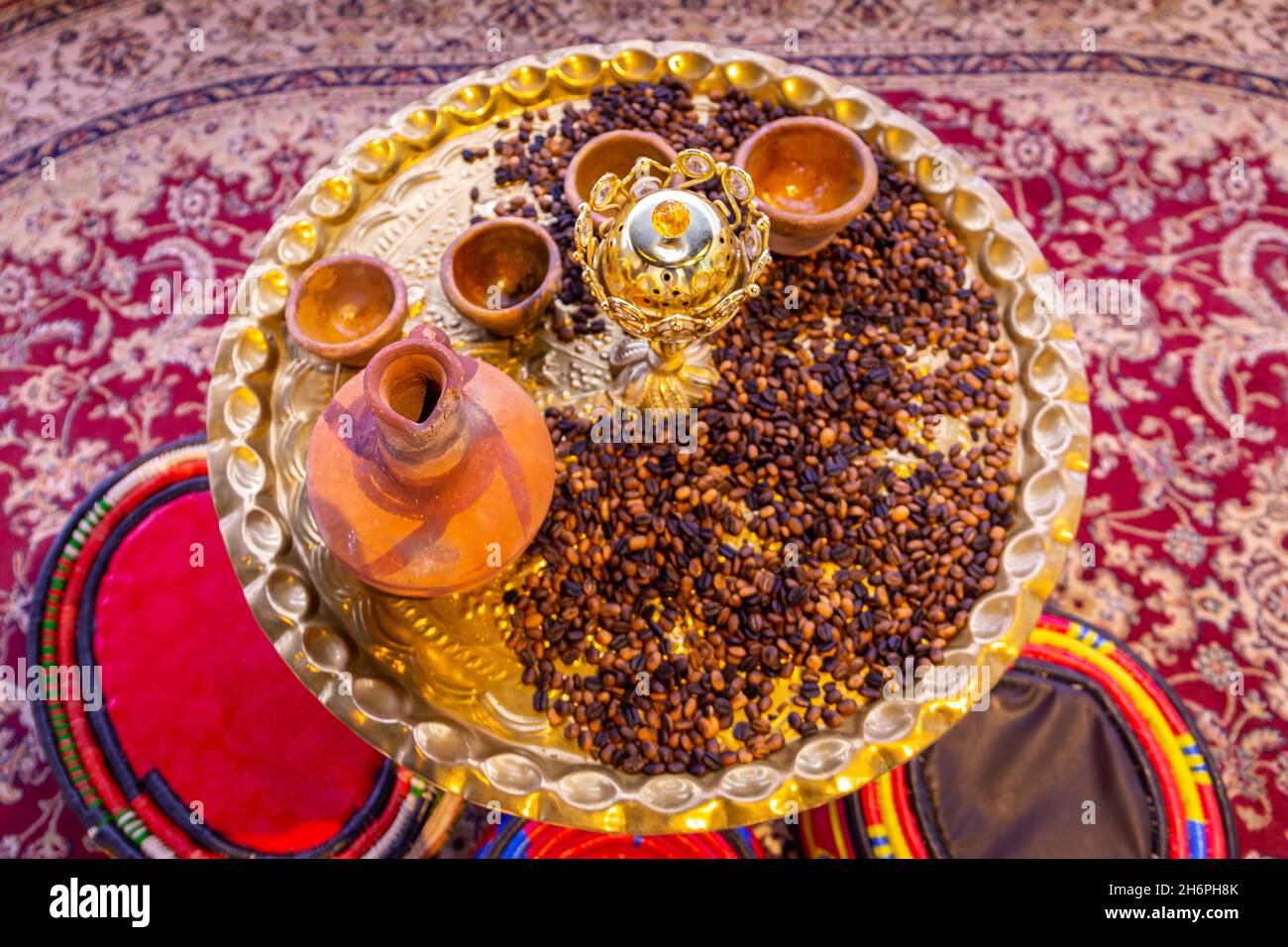 Caffe mocha coffee grains and arabic incenses on a golden tray with clay jugs and bowls, traditional Yemeni coffee table with colorful arabic majlis. Stock Photo