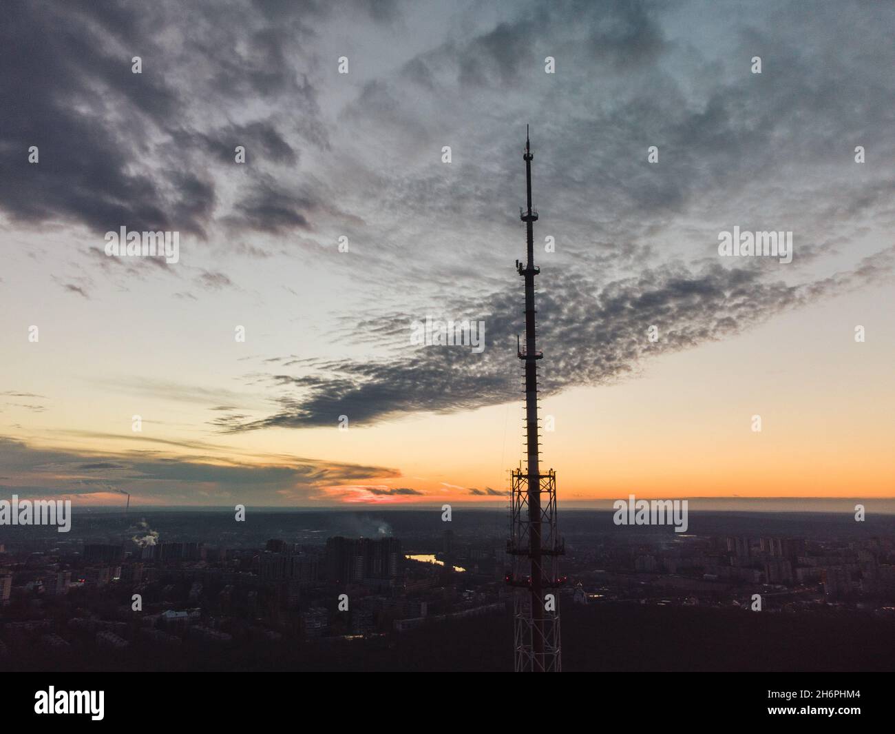 Aerial sunset evening city view on dark telecommunication tower antenna silhouette and scenic cloudy sky. Kharkiv, Ukraine Stock Photo