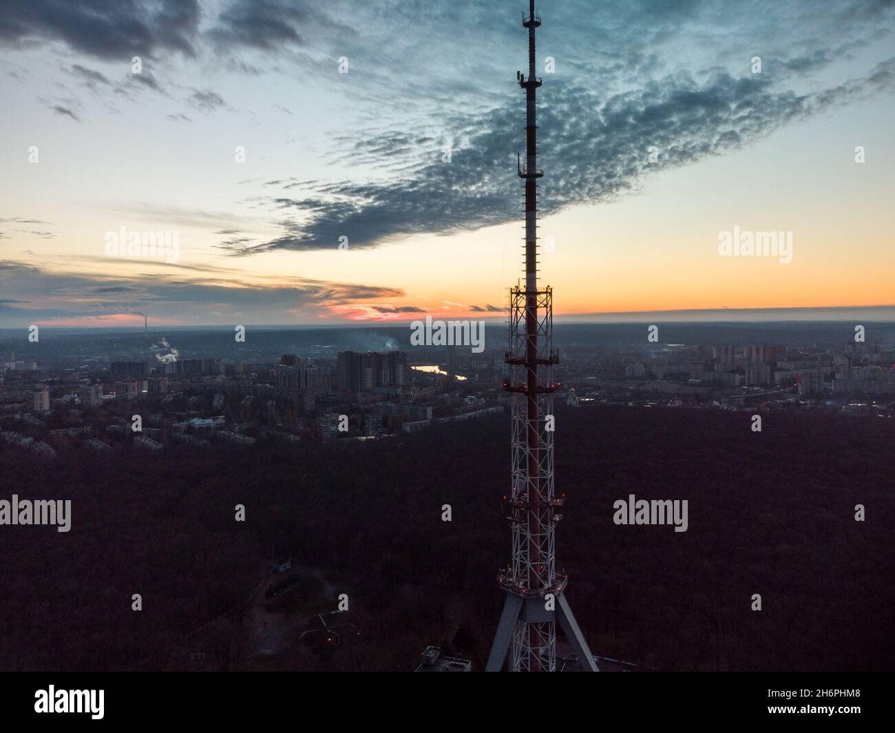 Aerial sunset evening view on forest with dark telecommunication tower antenna silhouette and scenic cloudy sky. Kharkiv, Ukraine Stock Photo