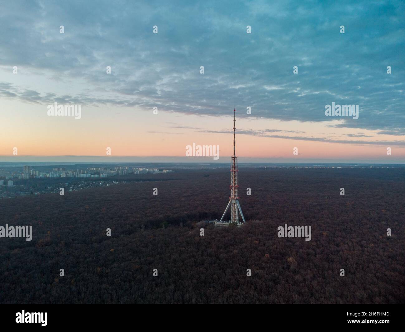 Aerial view after sunset, evening view on dark forest with telecommunication tower antenna and scenic cloudy sky. Kharkiv, Ukraine Stock Photo