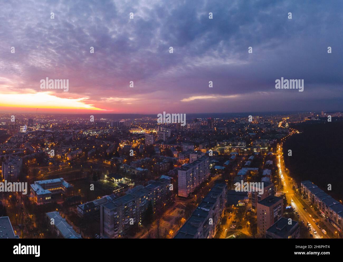 Aerial sunset scenic vibrant view on Kharkiv city, Pavlove pole. Night lights on streets of residential district and scenic cloudy purple sky after su Stock Photo