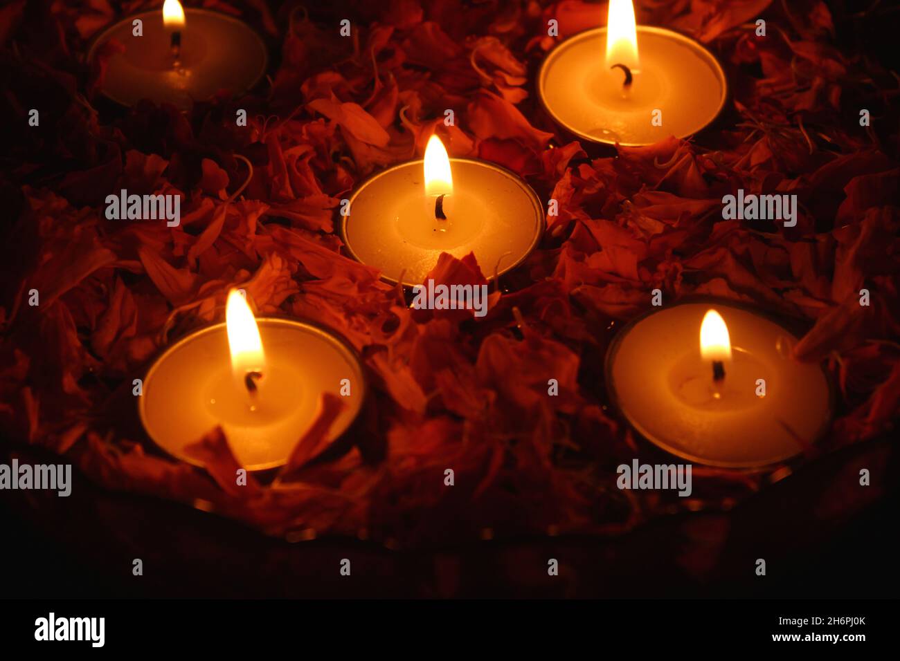 Burning tea lights and marigold flowers in a bowl in the dark Stock
