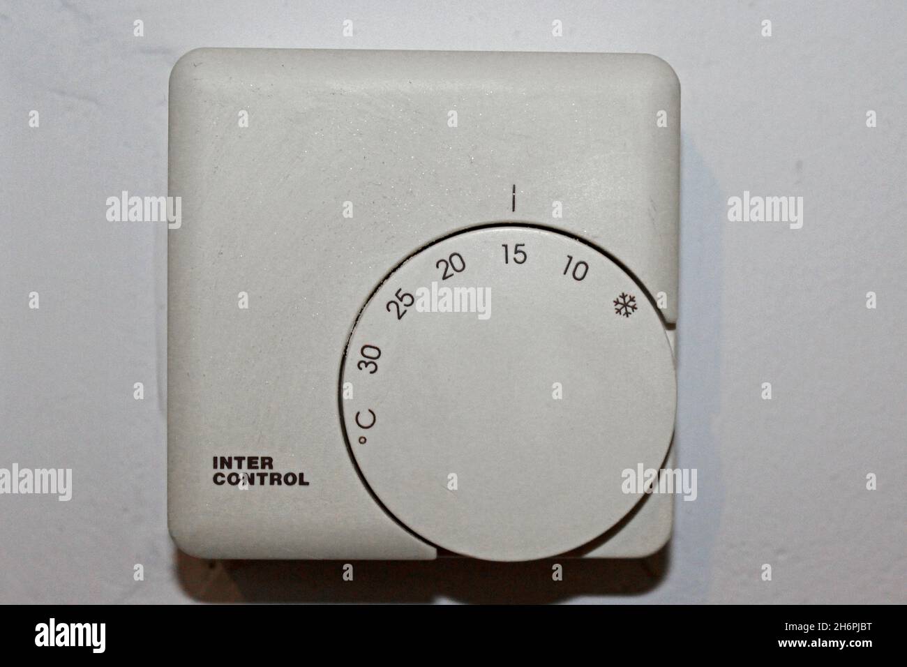Weißer Thermostat zur Wärmeregulierung von 0 bis 30 Grad einstellbar, in einer Wohnung an einer Wand, auf 15 Grad eingestellt. Stock Photo